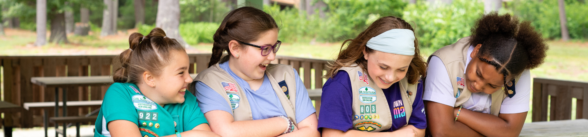  three young girl scouts with their arms wrapped around one another and smiling at the camera 